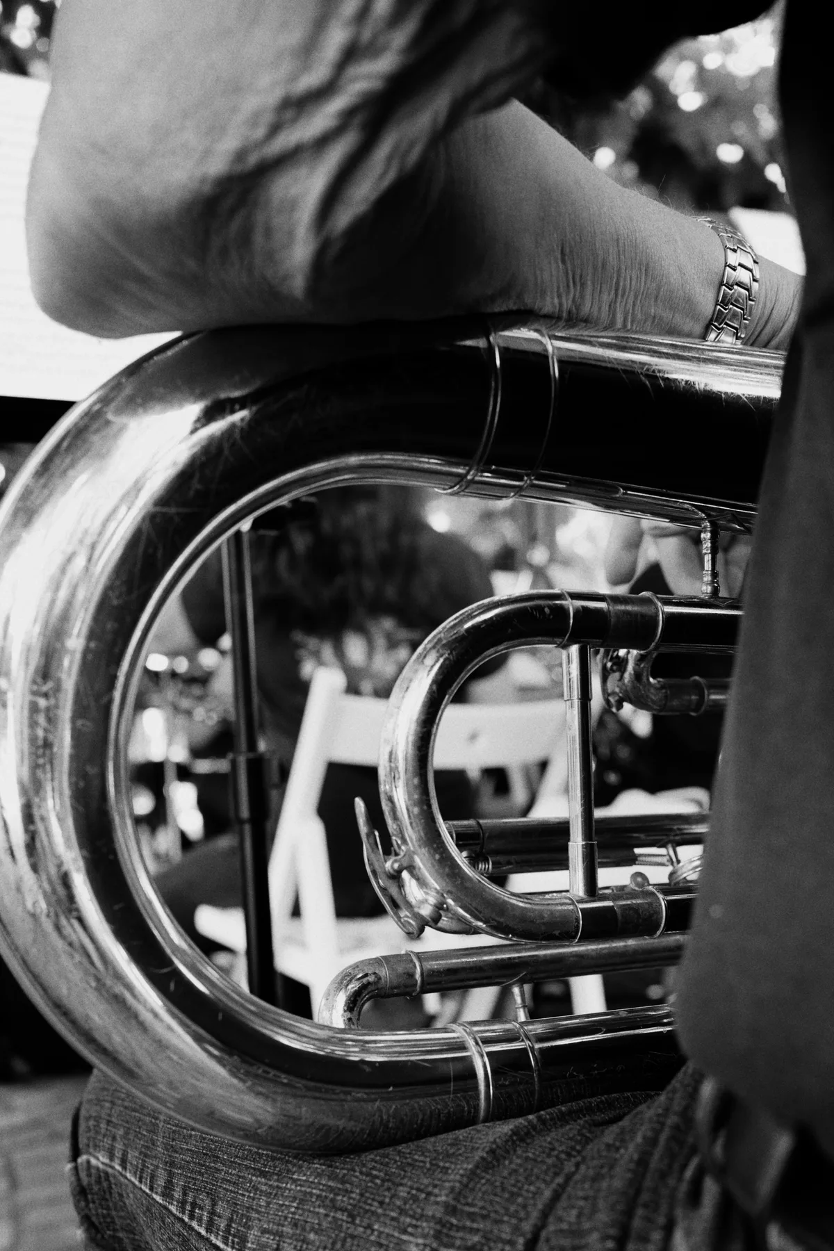 A black-and-white close-up of a brass instrument resting on a musician's lap.