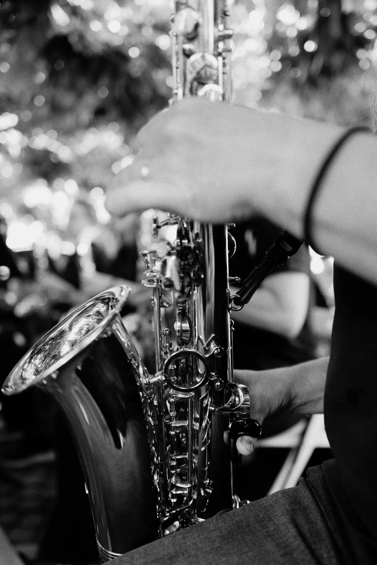 A close-up of a musician playing a saxophone outdoors.